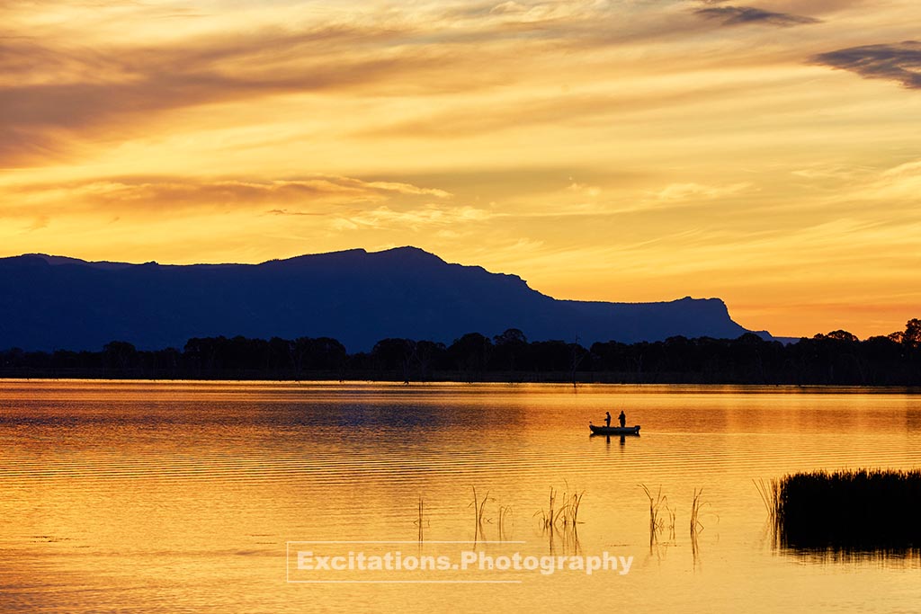 Sunset stock photo by excitations.au fishermen on a lake, mountains in background. Used as the feature image of photography for beginners blog post.